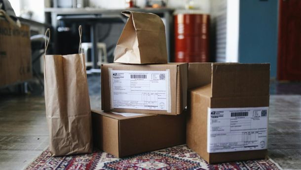 A collection of cardboard boxes and paper bags on a patterned rug in a home setting.