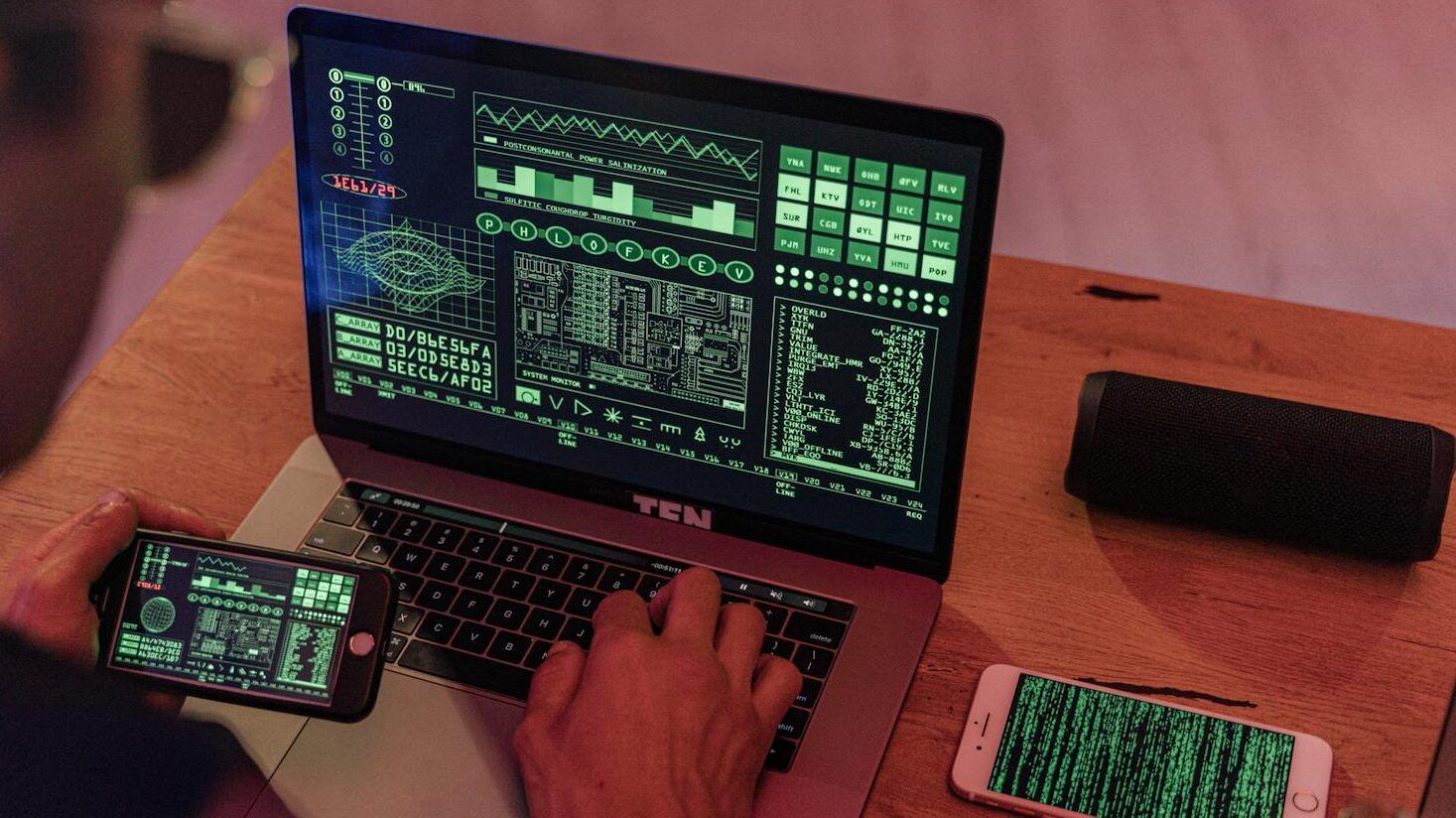 Man working with cybersecurity software on laptop and smartphone.