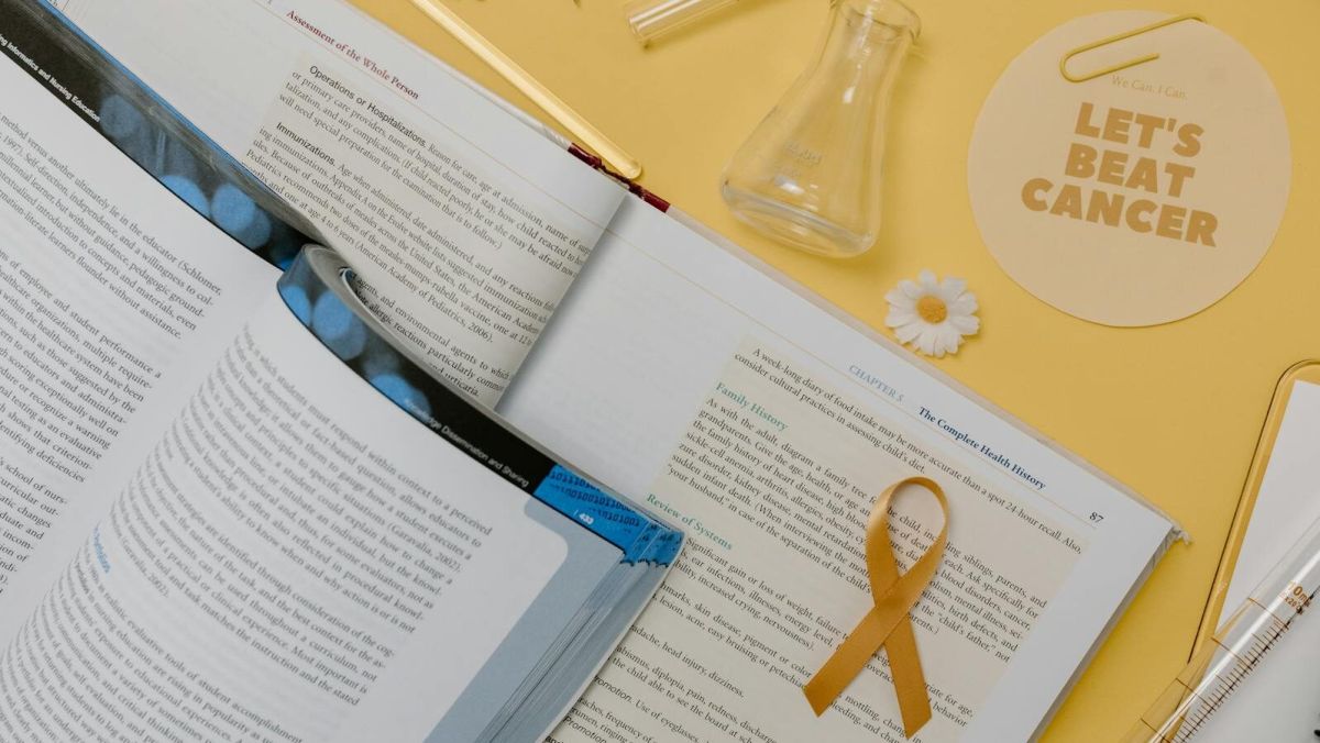 Flat lay of scientific research tools and gold ribbon for cancer awareness.