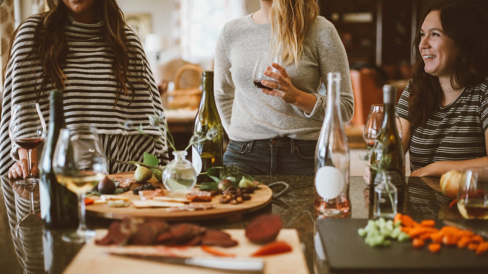 two woman standing beside woman sitting in front of table