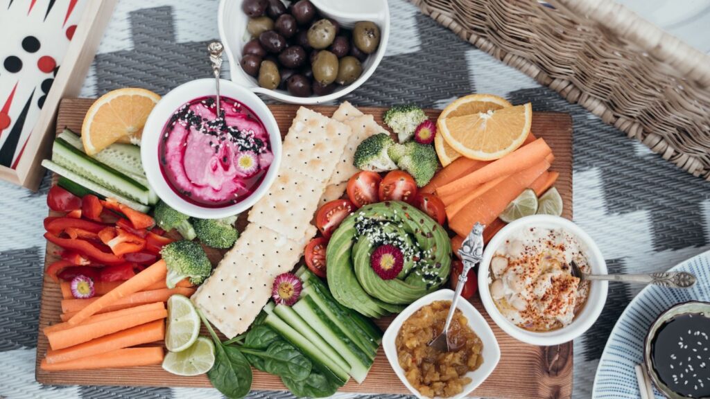 Colorful vegan platter featuring fresh vegetables, dips, and olives. Perfect for a healthy snack or party.