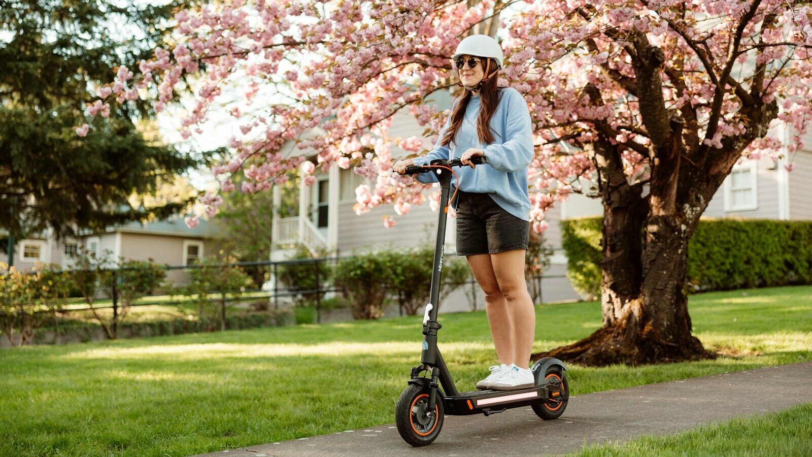 Woman rides an electric scooter in a beautiful park.