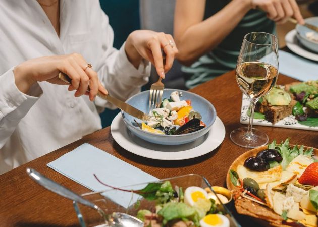 Elegant dining setting featuring fresh salad, dishes, and white wine, capturing a social gathering ambiance.