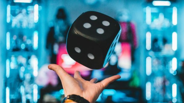 person's left palm about to catch black dice